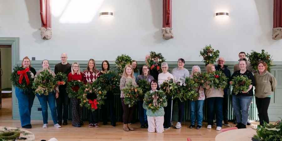 A group of people holding Christmas wreaths.