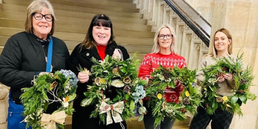 4 people holding wreaths in front of stairs.