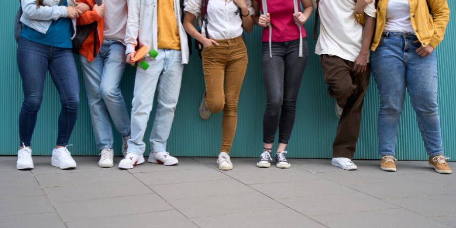 A group of people standing shoulder to shoulder, shown from the waist down.