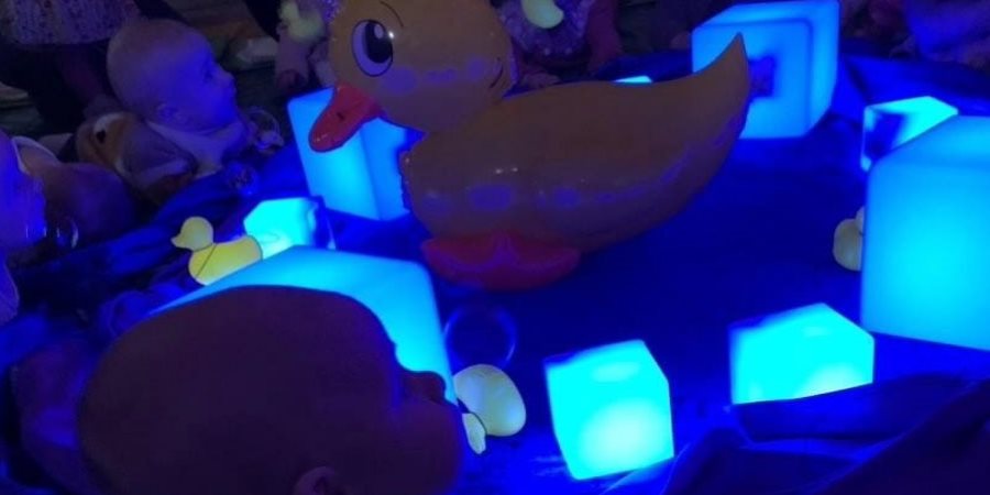 A baby in a dark room lit by soft lights.
