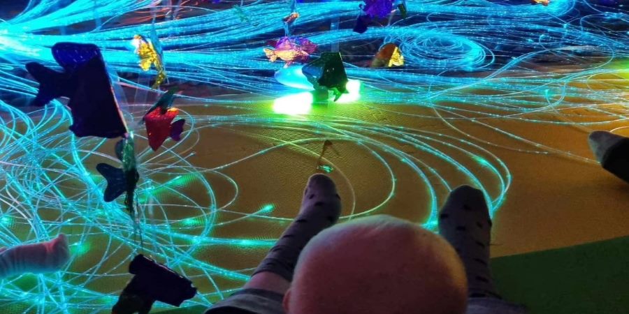 Baby sat in a room with a light display.