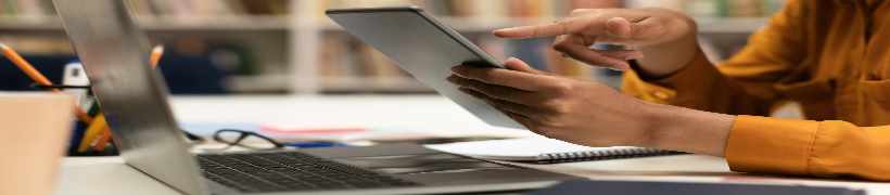 A woman using a tablet and laptop.