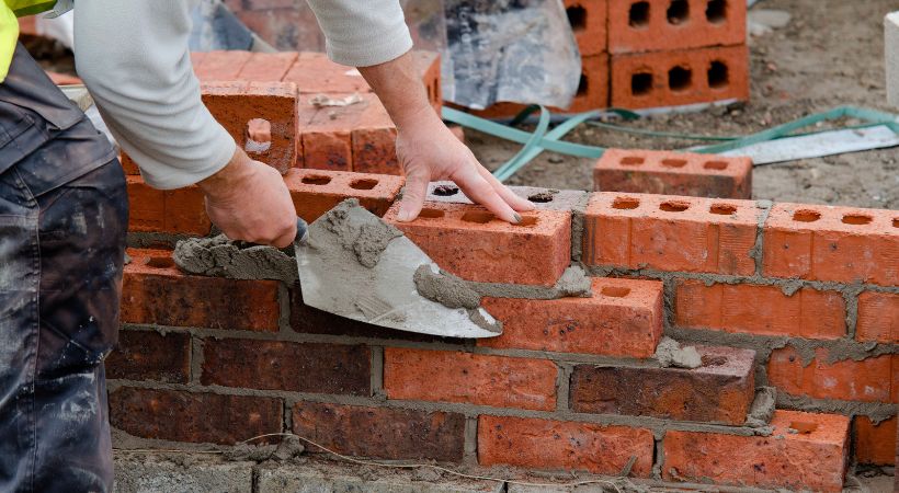 A brick layer constructing a brick wall.