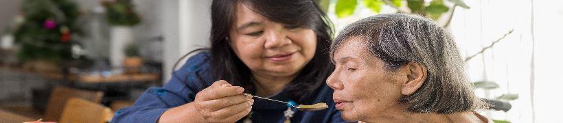 A carer feeding an elderly patient.