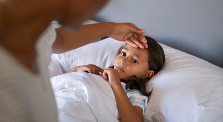A worried mother checks her daughter for a temperature with the back of her hand.