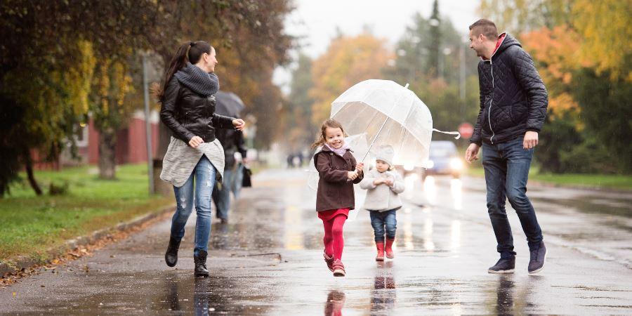 A family with children walking down the street on a rainy day.