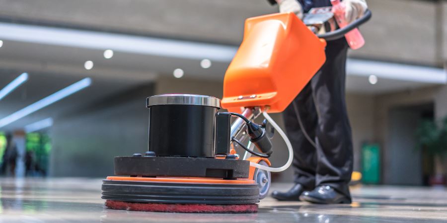 Close-up of a floor polishing machine being used in an office lobby.