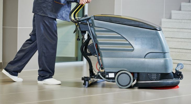 A cleaner cleaning the floor with a machine.