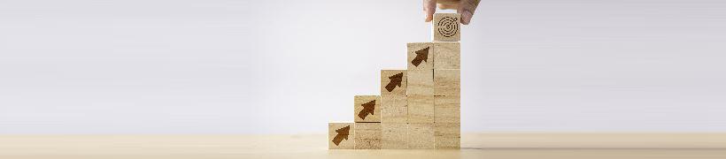 A hand placing a wooden block atop a staircase of blocks.