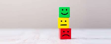 Stacked building blocks with happy, indifferent and sad faces.