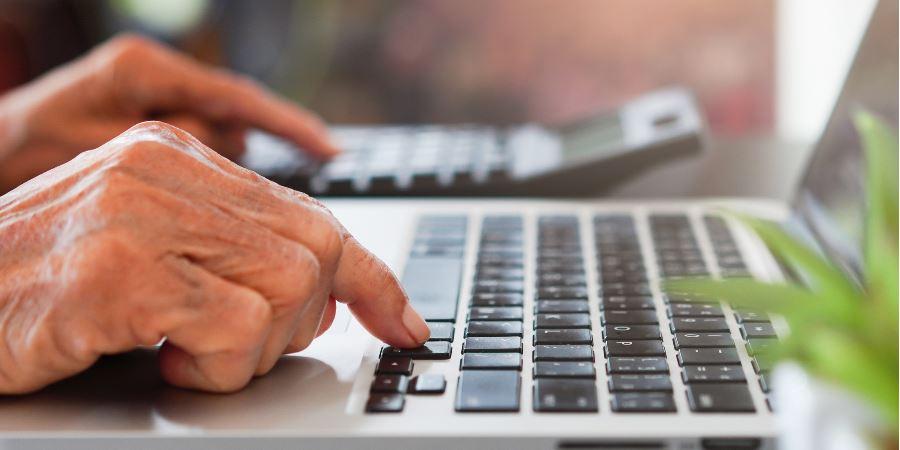 Close-up of hands typing on a laptop keyboard.