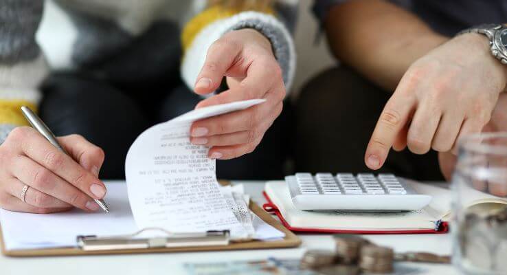 Close up of hands working on receipts and a calculator.