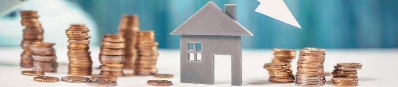 close up of piles of coins and a cutout of a house