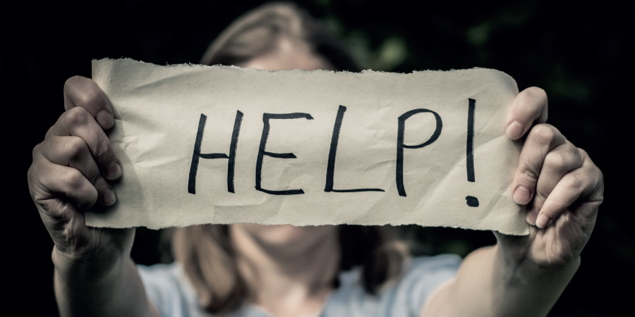 Person holding a help sign in front of their face.