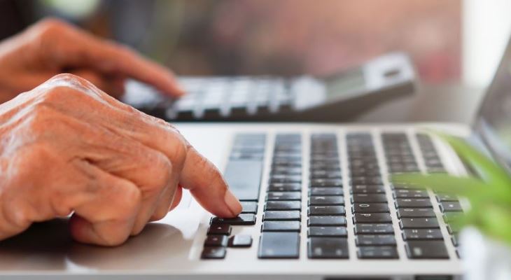 Hands working on a laptop keyboard.