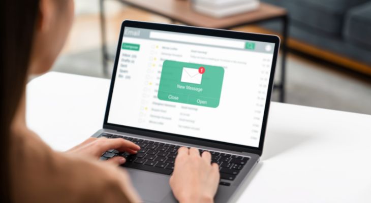 A woman using her computer on table with new email message on the screen.