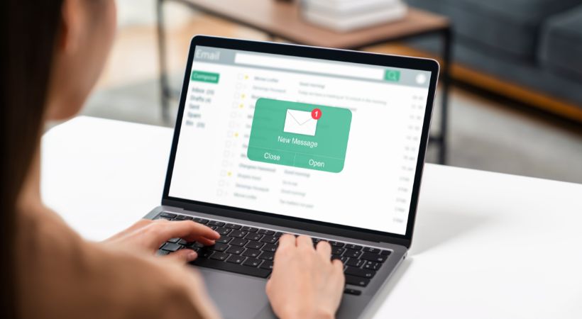 A woman using her computer on table with new email message on the screen.