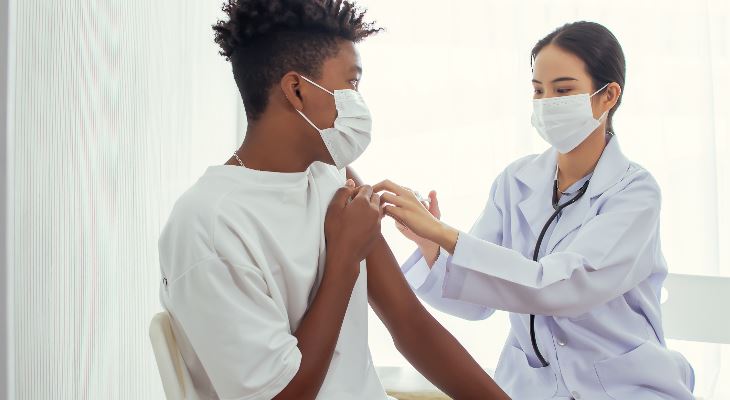 A young man receiving a vaccination from a nurse.