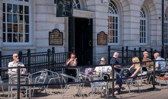 group of people sitting eating and drinking outside of a bar