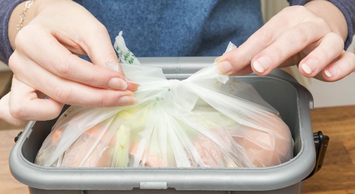 Hands tying a full food waste bag.