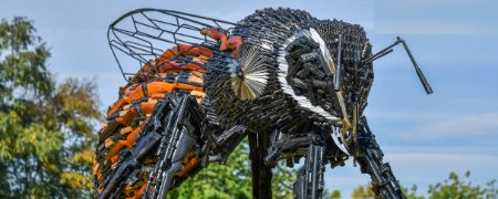 A statue of a bee made out of knives and guns.