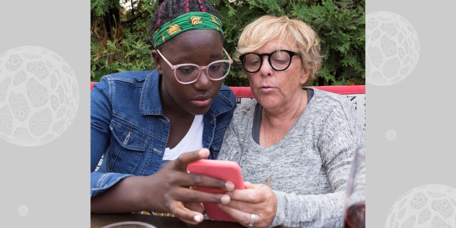 A girl and her mum looking at a mobile phone.