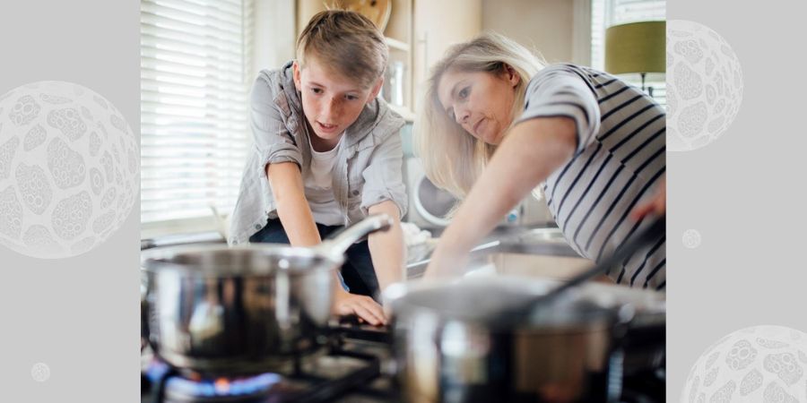 A lad and his mum turning on a gas stove.