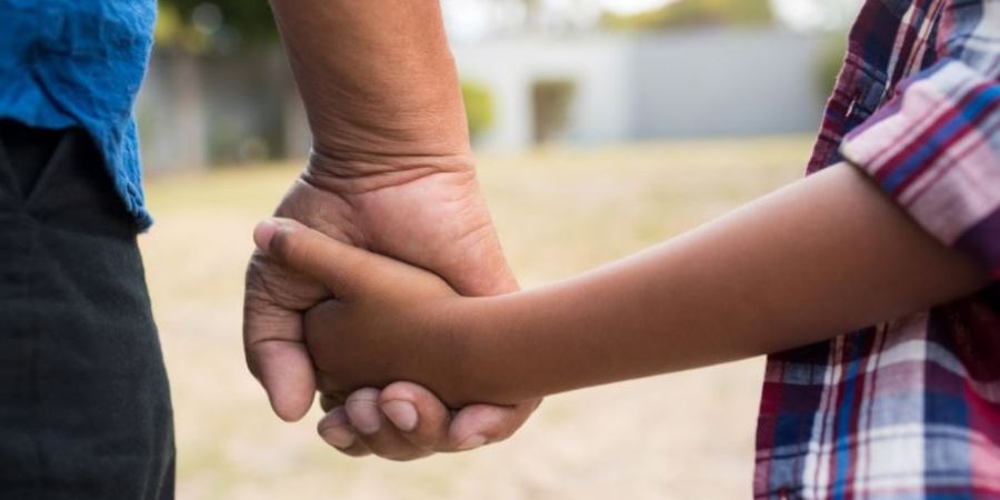 An adult holding a childs hand.