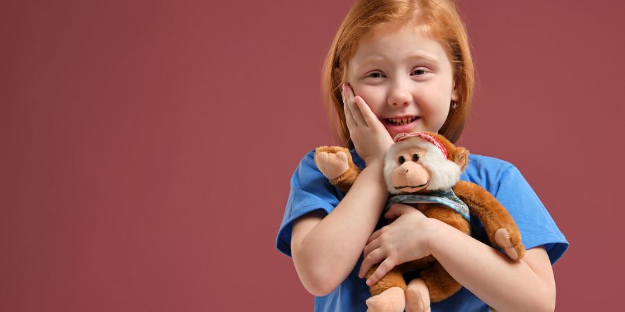 A young girl holding a toy monkey.