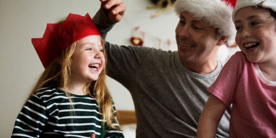 A girl, a boy and their dad wearing Santa hats.