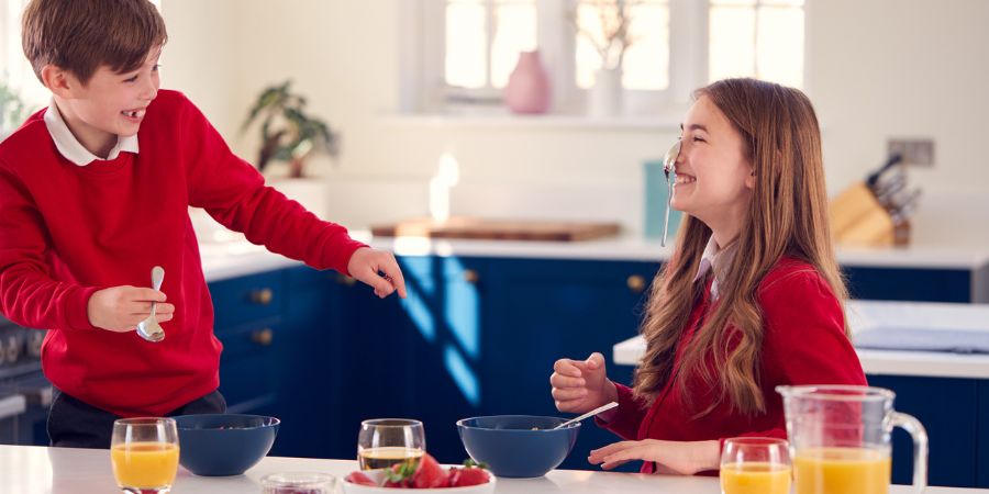 A brother and sister having fun at the breakfast table.