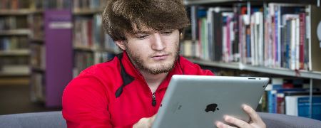 A man using a tablet in Rochdale Central Library.