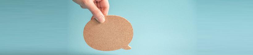 Hand holding a cutout of a speech bubble.