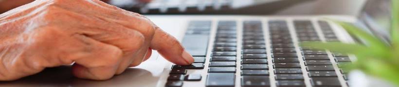 Close-up of hands working on a laptop.