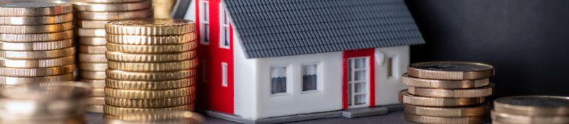 A model house next to stacks of coins, with a rising curve symbolising rising prices.