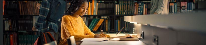 A young woman sitting working in a library.