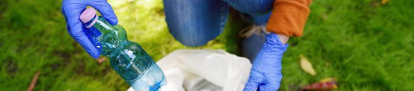 Close up of hands dropping a plastic bottle into a litter sack.