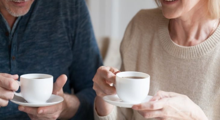 2 adults chatting over coffee.