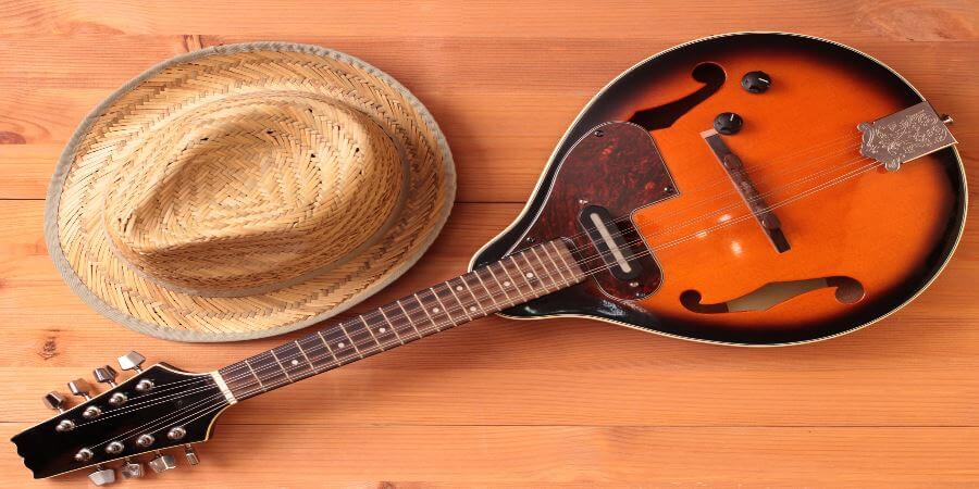 A mandolin lying next to a straw hat.