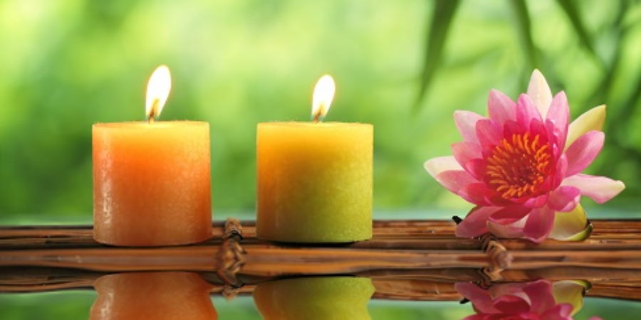 2 candles next to a tropical flower.