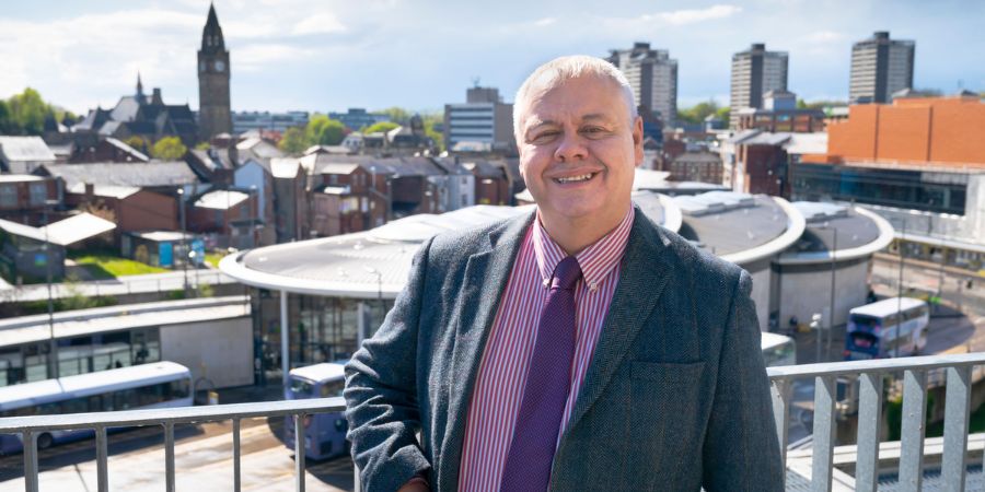 Leader of the council, Councillor Neil Emmott, standing in front of the Rochdale skyline.