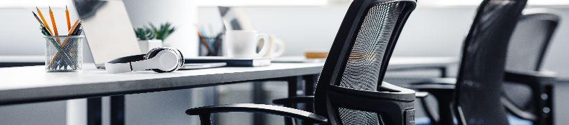 Office chairs resting in front of a bank of desks.