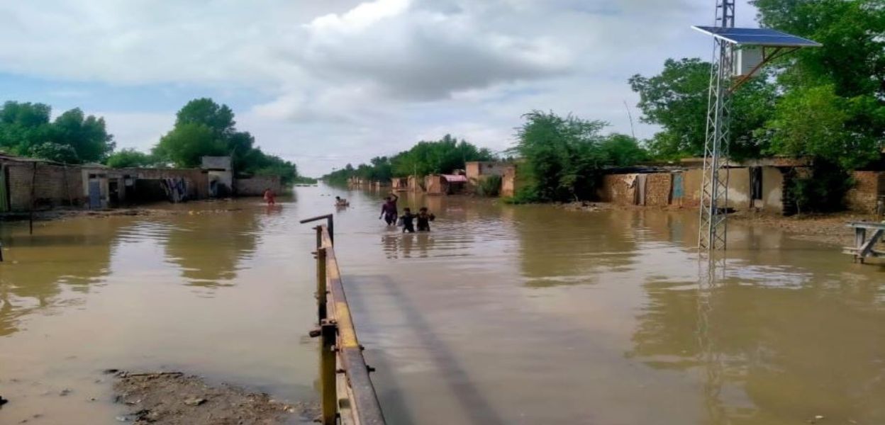 A family walking on a flooded road in Pakistan.