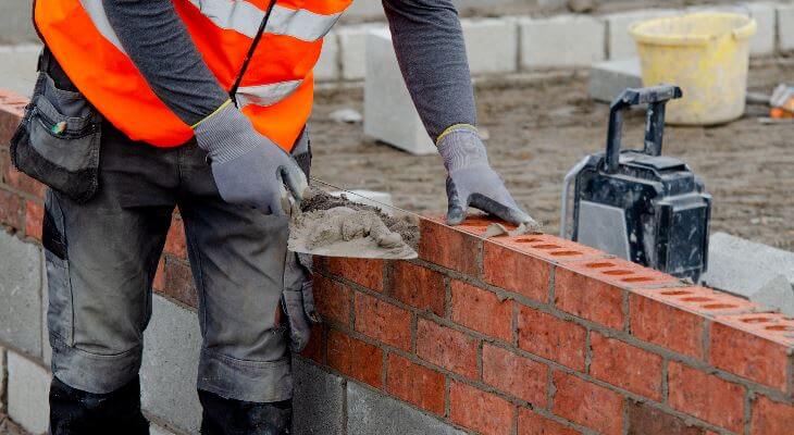 A bricklayer laying a row of bricks.