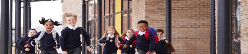 Primary school children running outside school.