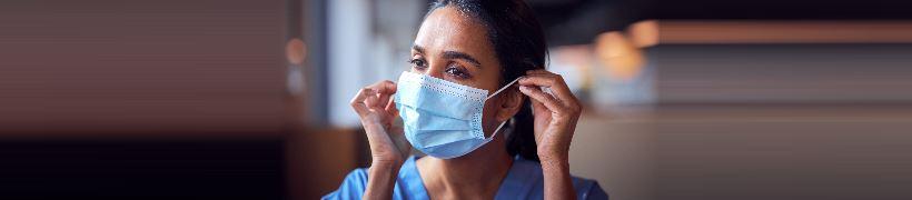 A nurse putting on a surgical mask.