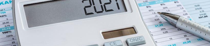 A calculator sitting on top of finance sheets alongside a pen.