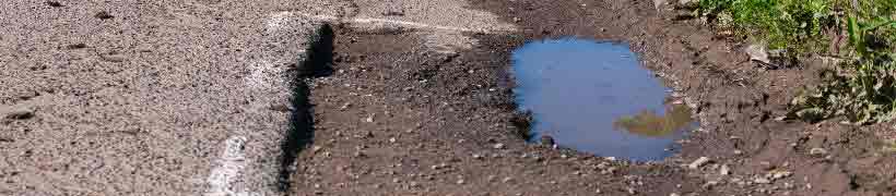 A pothole in a road marked for repair.