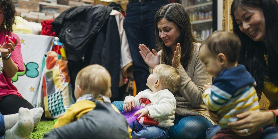 Parents and toddlers clapping along at a play session.