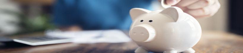 A person depositing a coin into a piggy bank.